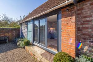 uma porta de vidro deslizante no lado de um edifício de tijolos em Romantic cottage in pretty village with great pubs - Stoke Cartlodge em Colchester