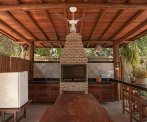 an outdoor kitchen with a fireplace and a wooden ceiling at Residencial Maria Pitanga in Arraial d'Ajuda