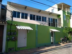 阿拉亚尔-杜卡布Acomodações Araujo的一座绿色建筑,前面停有一辆摩托车