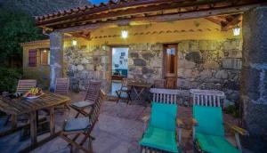 a patio with a table and chairs and a stone building at Casa Rural Cottage Bentayga in Tejeda