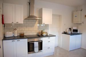 uma cozinha com armários brancos e um forno com placa de fogão em Wensum Cottage em Norwich