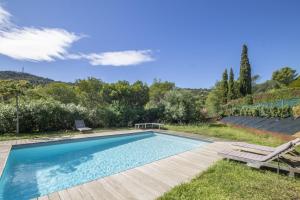 a swimming pool in a yard with a wooden deck at Bormes les Mimosas in Bormes-les-Mimosas