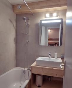 阿沃里亞茲的住宿－STUDIO CABINE COSY TRÈS CALME RÉSIDENCE ALPAGES 2 AU PIED DES PISTES，一间带水槽、浴缸和镜子的浴室