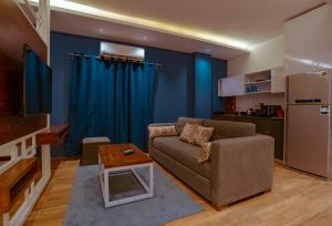 Travelholic Residence New Cairo في القاهرة: غرفة معيشة مع أريكة ومطبخ