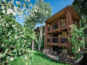 uma casa de madeira com um deque e árvores em Lift One - Updated Cozy Top Floor Two-bedroom With Mountain View em Aspen