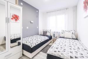 a bedroom with two beds and a mirror at Apartman Lotta in Vukovar