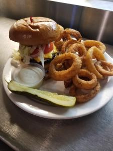 a plate with a sandwich and onion rings and a pickle at O'Cairns Inn and Suites in Lompoc