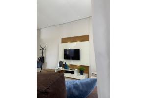 sala de estar con sofá y TV en la pared en Suíte Master Collection, en Passo Fundo