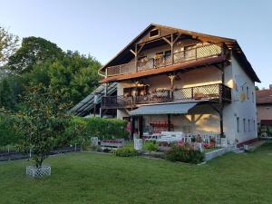 a large house with a balcony and a yard at Villa-Negra Retro Panzió in Balatonföldvár