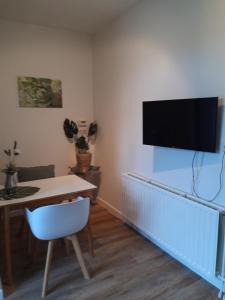 een woonkamer met een tafel en een televisie aan de muur bij Vakantiewoning 100m van het strand met 1 Slaapkamer in Westkapelle