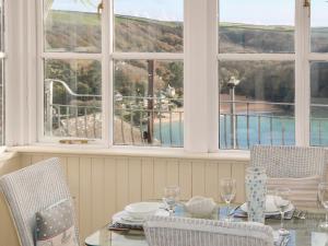 a dining room with a table and chairs and windows at The Keel Row in Salcombe