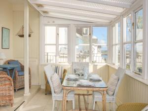 a dining room with a table and chairs and windows at The Keel Row in Salcombe