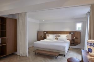 um quarto com uma cama com lençóis brancos e almofadas brancas em Hôtel du Sentier em Paris