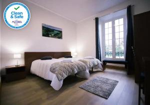a bedroom with a bed and a large window at Cantinho do Pensamento in Ribeira Grande