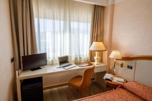 a hotel room with a desk with a computer and a bed at Perugia Plaza Hotel in Perugia