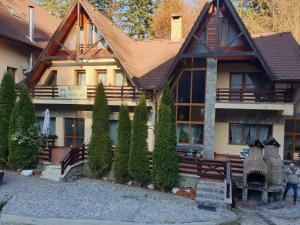 a house with a fence and trees in front of it at Pensiunea Eliza in Sinaia