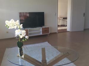 a living room with a glass table with a vase of flowers at Ferienwohnung Paradies in Nollingen +11 photos