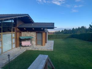 ein Haus mit einer Rasenfläche mit einer Bank im Hof in der Unterkunft Pirin Golf Villa Emila in Bansko