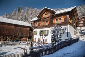 a wooden house in the snow with a fence at Casa Curgnun 21 Collenberg - Ferienwohnung 61m2 für max. 4 Pers. in Morissen