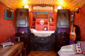 Un dormitorio con una cama y una guitarra en una habitación en La Roulotte de la Fay, en Dompierre-les-Ormes