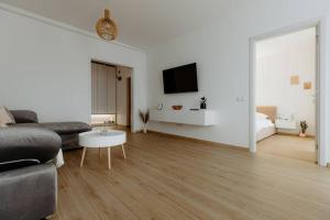 ein weißes Wohnzimmer mit einem Sofa und einem TV in der Unterkunft Oasis Residence in Baia Mare