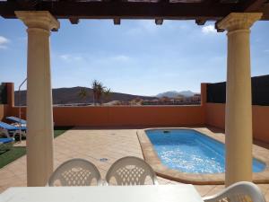un patio con piscina y 2 sillas en Casa Miel, en Corralejo