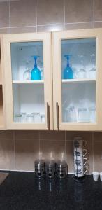a kitchen counter with blue vases in glass cabinets at Mbuso Guest House in Richards Bay