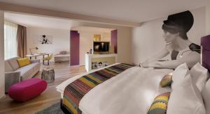 uma mulher sentada em cima de uma cama num quarto em Hotel Indigo - Dusseldorf - Victoriaplatz, an IHG Hotel em Dusseldorf