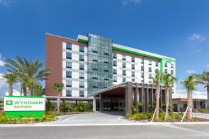 a hotel with palm trees in front of a building at Wyndham Garden Orlando Universal / I Drive in Orlando