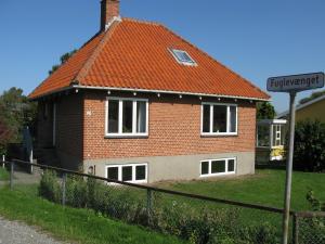 ein Backsteinhaus mit einem orangenen Dach und einem Straßenschild in der Unterkunft Fuglevænget in Hundested