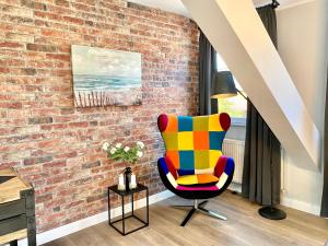 - une chaise colorée dans une chambre dotée d'un mur en briques dans l'établissement Schöne Ferienwohnungen teilweise mit Dachterrasse im Herzen von Itzehoe, à Itzehoe