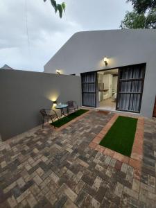 une terrasse avec une table et des chaises devant un bâtiment dans l'établissement The Homestead, à Bloemfontein