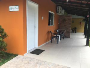 un porche de una casa con sillas y una pared de color naranja en Refúgio do Bosque, en Penha