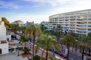 a city street with palm trees in front of a building at Jardines Puerto Banus Rooms in Marbella