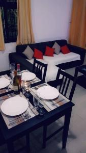 a table with plates and wine glasses and a couch at Residence Frangipani in Pereybere