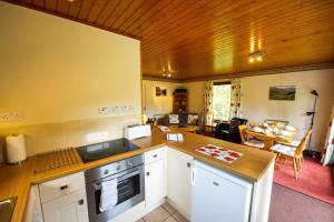 a kitchen with a counter top and a living room at Heron chalet in Crianlarich