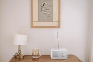 a table with a lamp and a alarm clock on it at Les Suites de Catherine, la 35 in Nancy