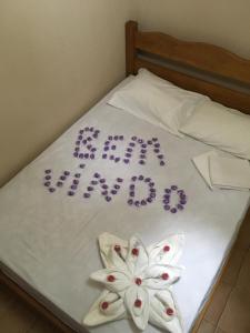 - un lit avec des draps blancs et des fleurs violettes dans l'établissement Food park Guaramiranga, à Guaramiranga