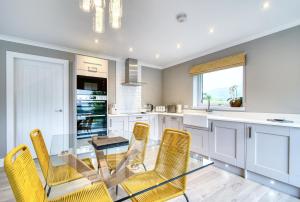 a kitchen with a glass table and yellow chairs at Stunning 5 star chalet with loch views in Crianlarich