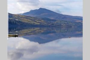 um reflexo de uma montanha num grande lago em Cosy Minffordd Let - Llanuwchllyn near, Bala LL23 em Bala