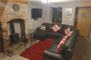 a living room with a black leather couch and a fireplace at Cosy Minffordd Let - Llanuwchllyn near, Bala LL23 in Bala