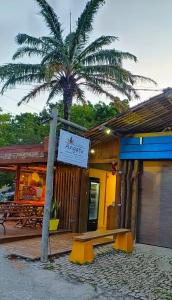 un restaurant avec un palmier en face d'un bâtiment dans l'établissement Pousada Angatu Arraial - Rua do mucugê, à Arraial d'Ajuda