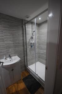 a bathroom with a shower and a white sink at Loch Lomond Riverside Apartment in Drymen