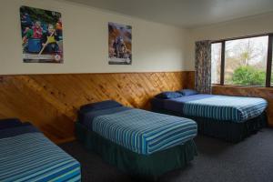 um quarto com três camas e cartazes na parede em National Park Backpackers em National Park