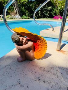 una mujer se arrodilla junto a una piscina en Posada del Angel, en Colonia del Sacramento