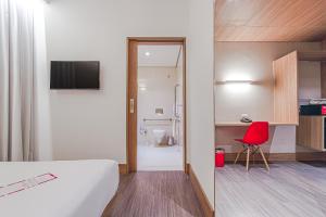 a hotel room with a bed and a red chair at Hotel Moov Curitiba in Curitiba