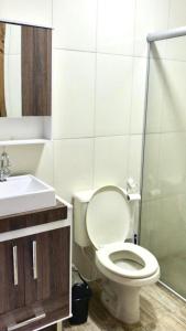 y baño con aseo blanco y lavamanos. en Apartamento aluguel temporada Torres-RS en Torres