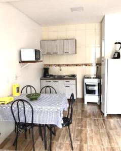 a kitchen with a table and chairs and a refrigerator at Apartamento aluguel temporada Torres-RS in Torres
