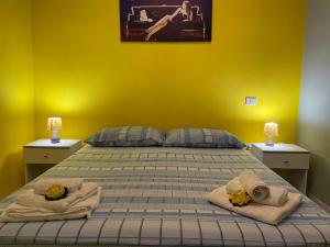1 dormitorio con 1 cama con toallas y pared amarilla en Baia Verde Apartment, en Baia Verde