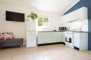 a kitchen with white appliances and a couch at Tasman Holiday Parks - Myola in Myola